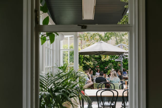 Looking through a doorway to a big table of friends dining at Dux Dine, Christchurch.