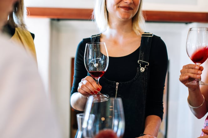 A woman holding a glass of red wine.