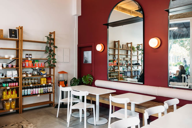 Interior details at Cream Eatery with large arched mirrors, white tables, and a shelf of artisan food products