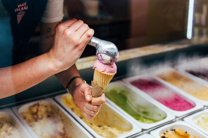 Someone putting two scoops of Duck Island ice cream onto cone