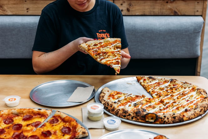Slice of pizza being picked up by a customer.
