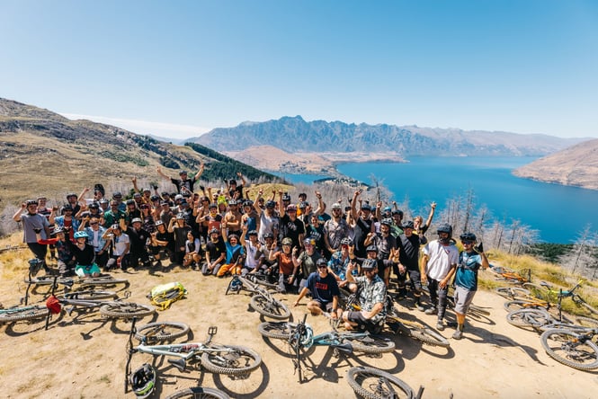 A large group of people smiling to camera with a lake behind them.