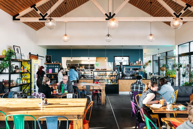 Customers fill the dining area and line up by the front counter and food cabinet at Industry Lane Eatery.