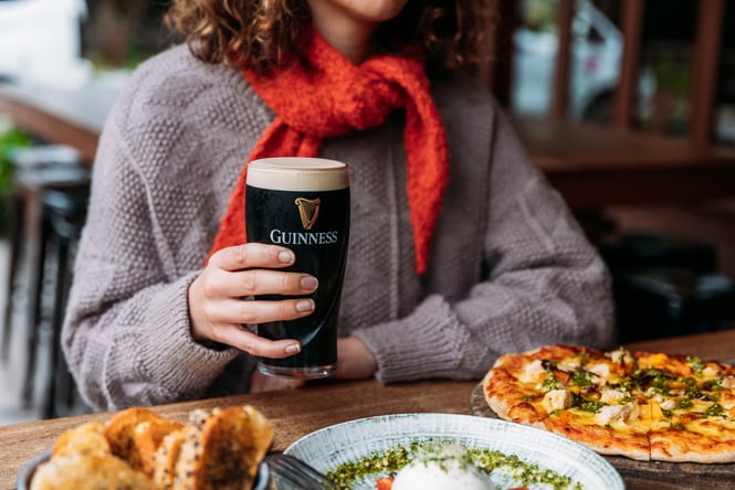 Customer sitting at a table with a pint of Guiness and plates of food at Paulina's Bar.
