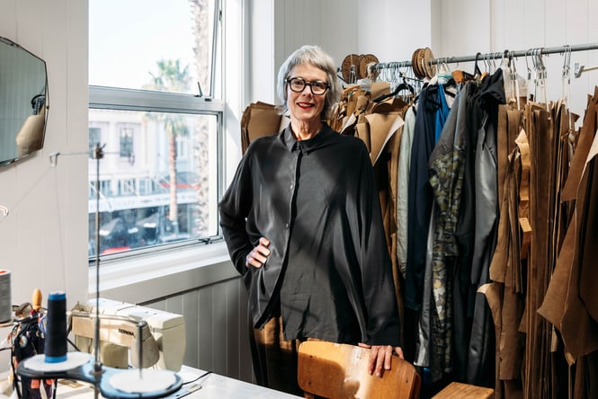A woman wearing black smiling to camera inside her store.