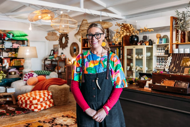 A woman smiling to camera inside a retail store.