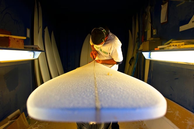 A man shaping a surfboard.