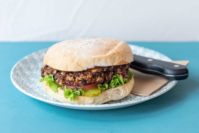 A veggie burger on a blue table.