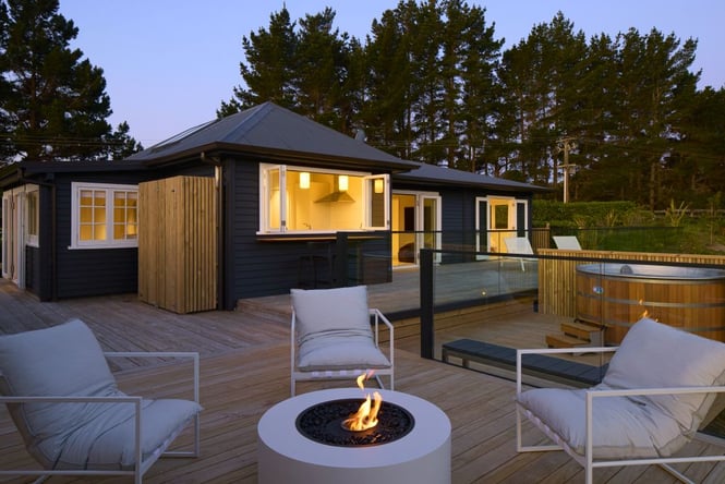 Fire pit with chairs around it, spa pool to the side and house in the background.