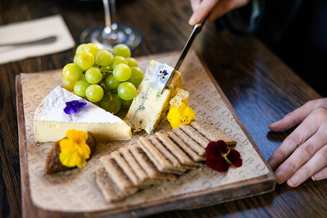 Customer cutting into a cheeseboard at OGB.