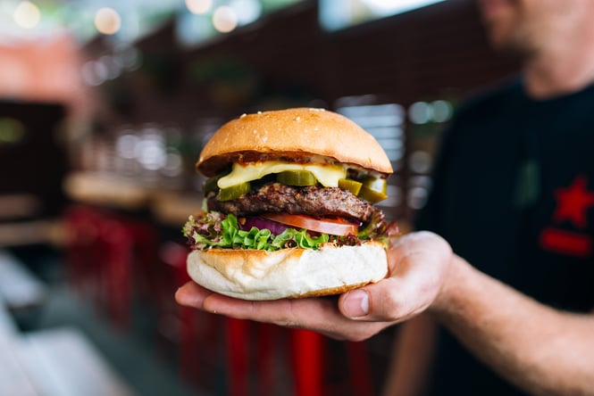 A hand holding a tasty looking burger.
