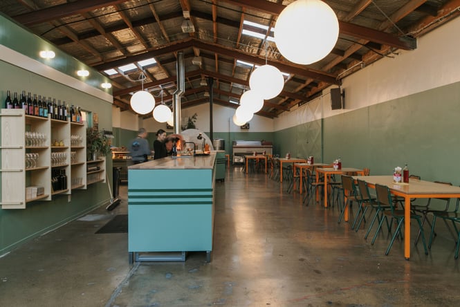 Overview of Lillies dining space with staff working behind counter and kitchen space