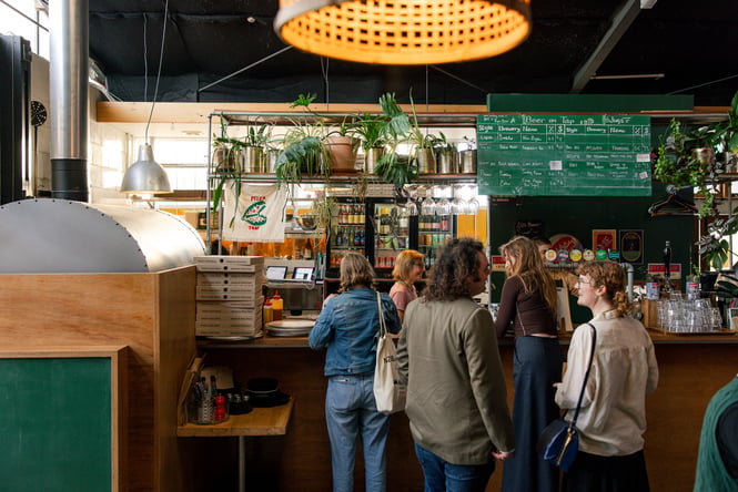 People lining up at the plant-filled bar area at Space Academy