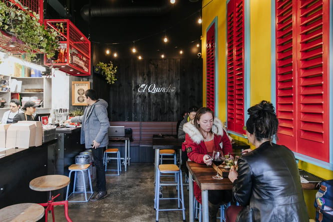 Customers dining inside El Quincho at high tables.
