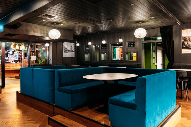 Blue velvet booth seating in the centre of the space with Irish flags on the wall in the background.