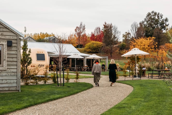 Two women walking through the grounds of Monte Christo Winery and outdoor tables in the background.