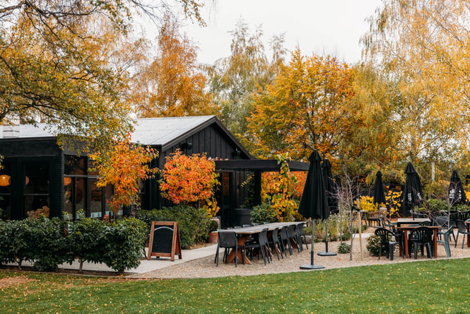 Outdoor tables and chairs in front of the building of The Orchard Garden Cafe.