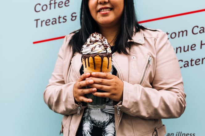 A woman holding a giant pastry ice cream.
