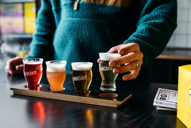 Customer selecting a glass from a tasting paddle.