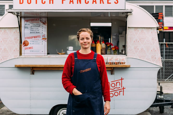 A woman smiling to camera with a hand in her apron pocket.