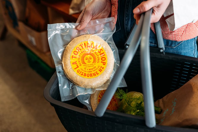 A close up of a hand holding a packet of tortillas.
