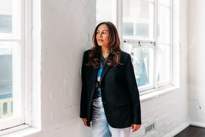 A woman leaning up against a brick wall painted white.
