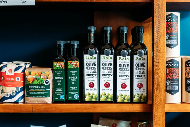 Pantry items including bottles of olive oil on display on a shelf.