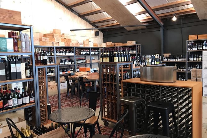 The interior of decant, with shelves filled with bottles of wine on black metal shelves.