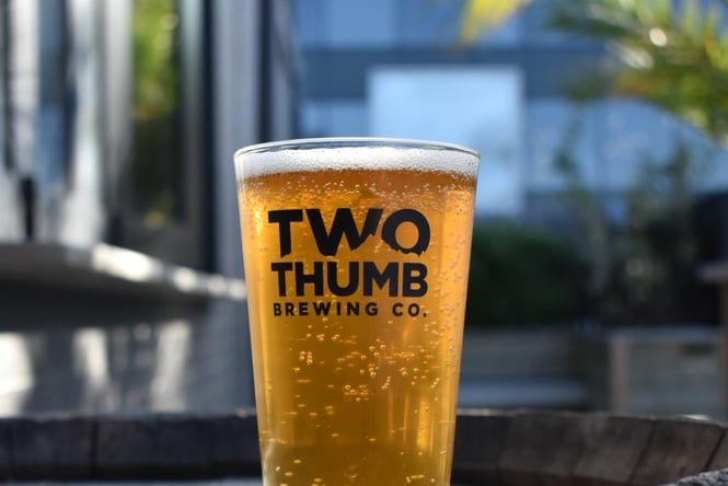 Close-up of a glass with a black logo on it filled with beer.