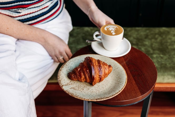 Customer enjoying a coffee and croissant at Glou Glou.