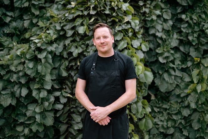 James standing in front of a wall of ivy leaves.
