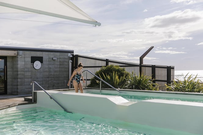 Woman walking into hot pool at He Puna Taimoana in New Brighton