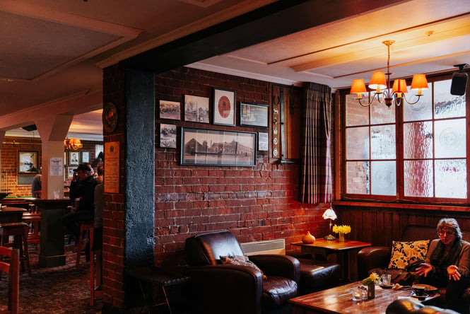 Cosy interior of Pomeroy's in Christchurch with leather sofas, low lighting and brick walls.