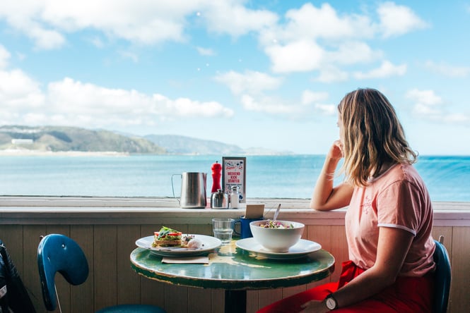 Woman enjoying her breakfast while looking out towards Lyall Bay in Wellington