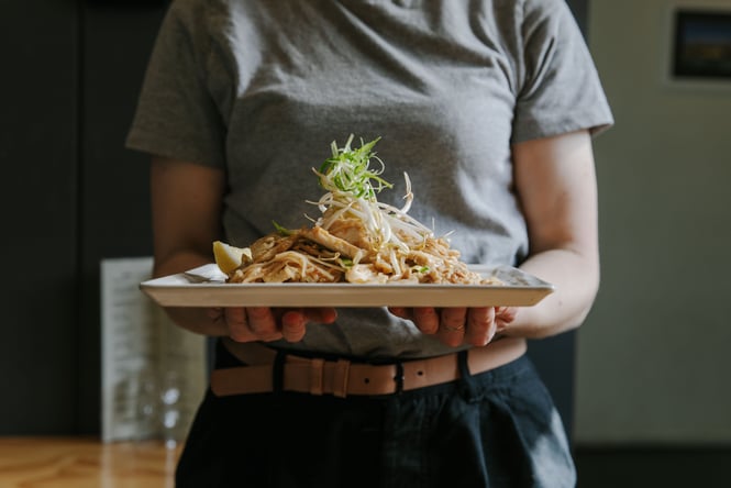 A person holding a plate of Thai food.