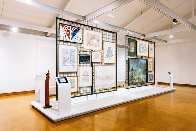 A black metal frame covered with art works on display.