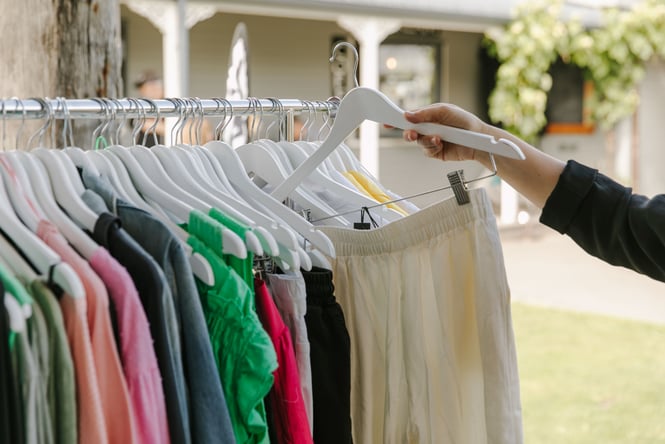 Hand picking up a pair of trousers off rack at Mint Boutique, Fairlie.