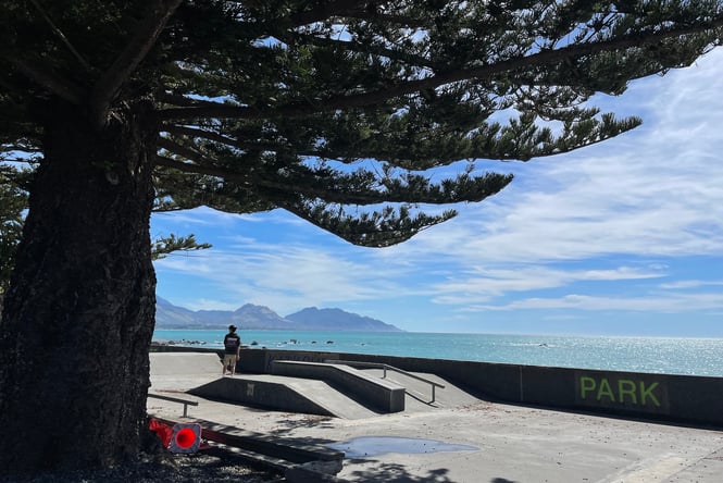 A skate park right next to the ocean on a grey and wet day.