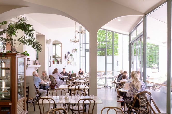 Dining room space with people sitting at tables and chairs.