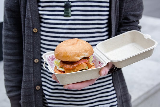 A man holding a vegan burger from Wise Boys in Auckland.