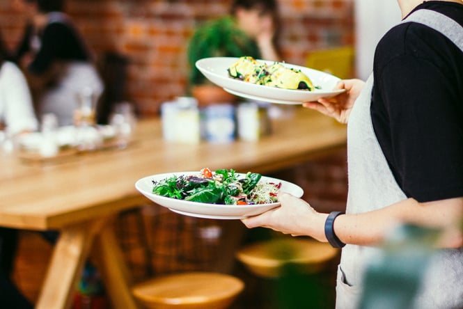 A staff member carrying two plates of food.