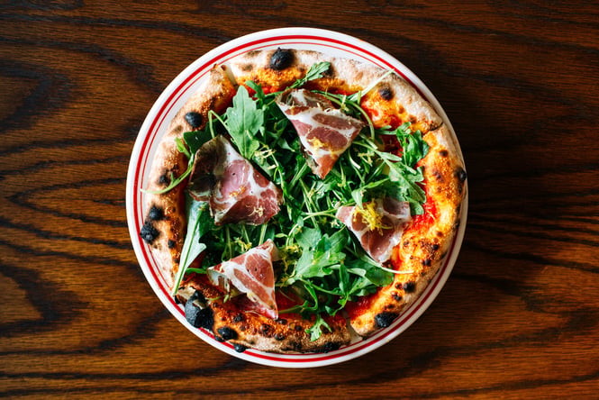 A flatlay of a pizza on a table at Ombra Wellington.