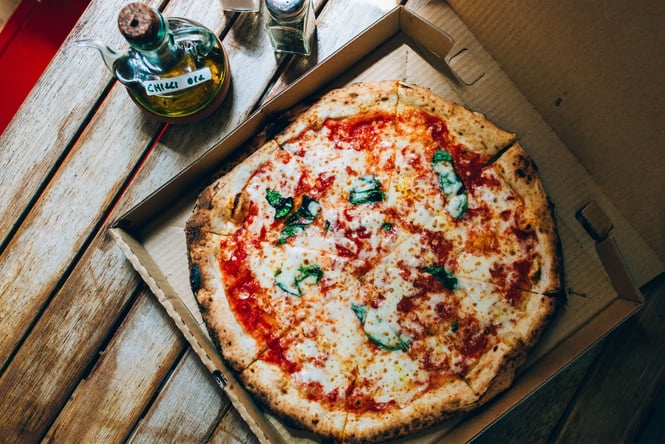 A flatlay of pizza on a table next to a bottle of chilli oil at Pizza Pomodoro Wellington.