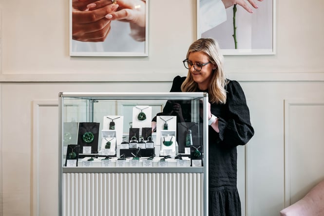 A shop assistant getting an item out of the jewellery cabinet..