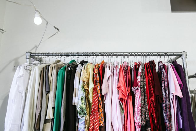 A rack of clothing lined up in the order of the colours of the rainbow.