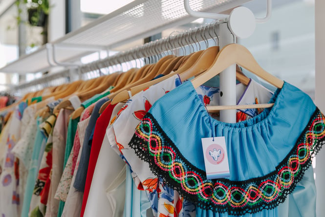 A close of brightly coloured clothes on a rack.