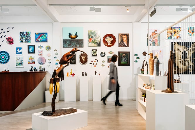 Looking through the Zimmerman Art Gallery where there is a sculpture of a red dear next to a green leaf covered artwork.