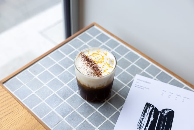 Cold foam specialty drink on table next to menu at Rook cafe