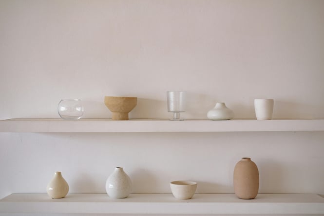 Glass and ceramic small vases, bowls and tumblers displayed on white shelving.