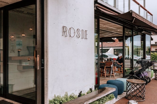 Exterior concrete wall of Rosie with 'ROSIE' in metal lettering.
